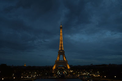 Low angle view of illuminated tower against cloudy sky