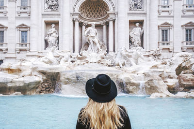 Rear view of woman standing against trevi fountain