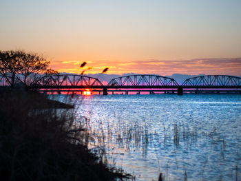 Bridge over river against sky during sunset