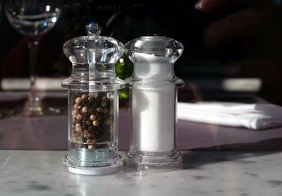 Close-up of salt and peppercorn in glass cellar on table