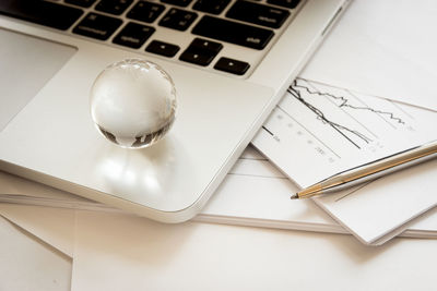 High angle view of globe with laptop and files on table