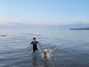 High angle view of boy playing with dog in lake