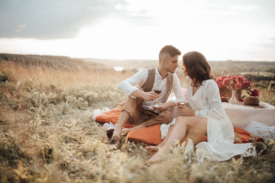 Friends sitting on land against sky