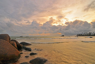 Scenic view of beach against cloudy sky