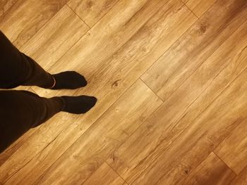 Low section of man standing on wooden floor