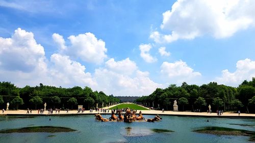 Panoramic view of people by trees against blue sky