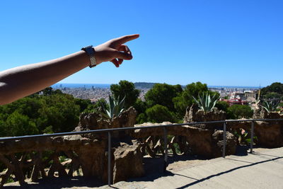 Low angle view of hand against built structure against blue sky