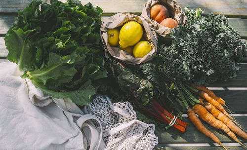 Fresh organic leafy vegetables and fruits on wooden table