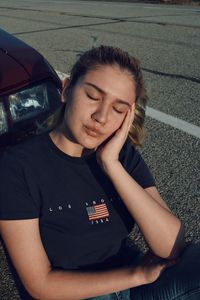 Young woman sitting on car