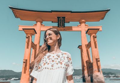 Low angle view of woman standing against tori gate