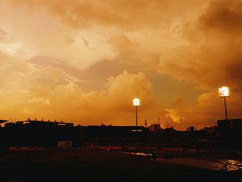 Silhouette of street light against cloudy sky