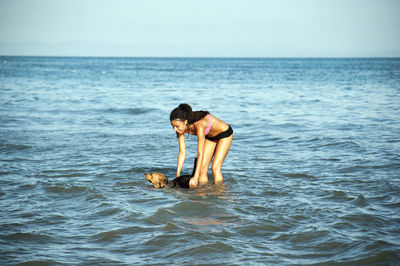 Happy girl with afro hairstyle, playing with a dog on the beach person