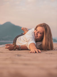 Portrait of young woman lying down against sky