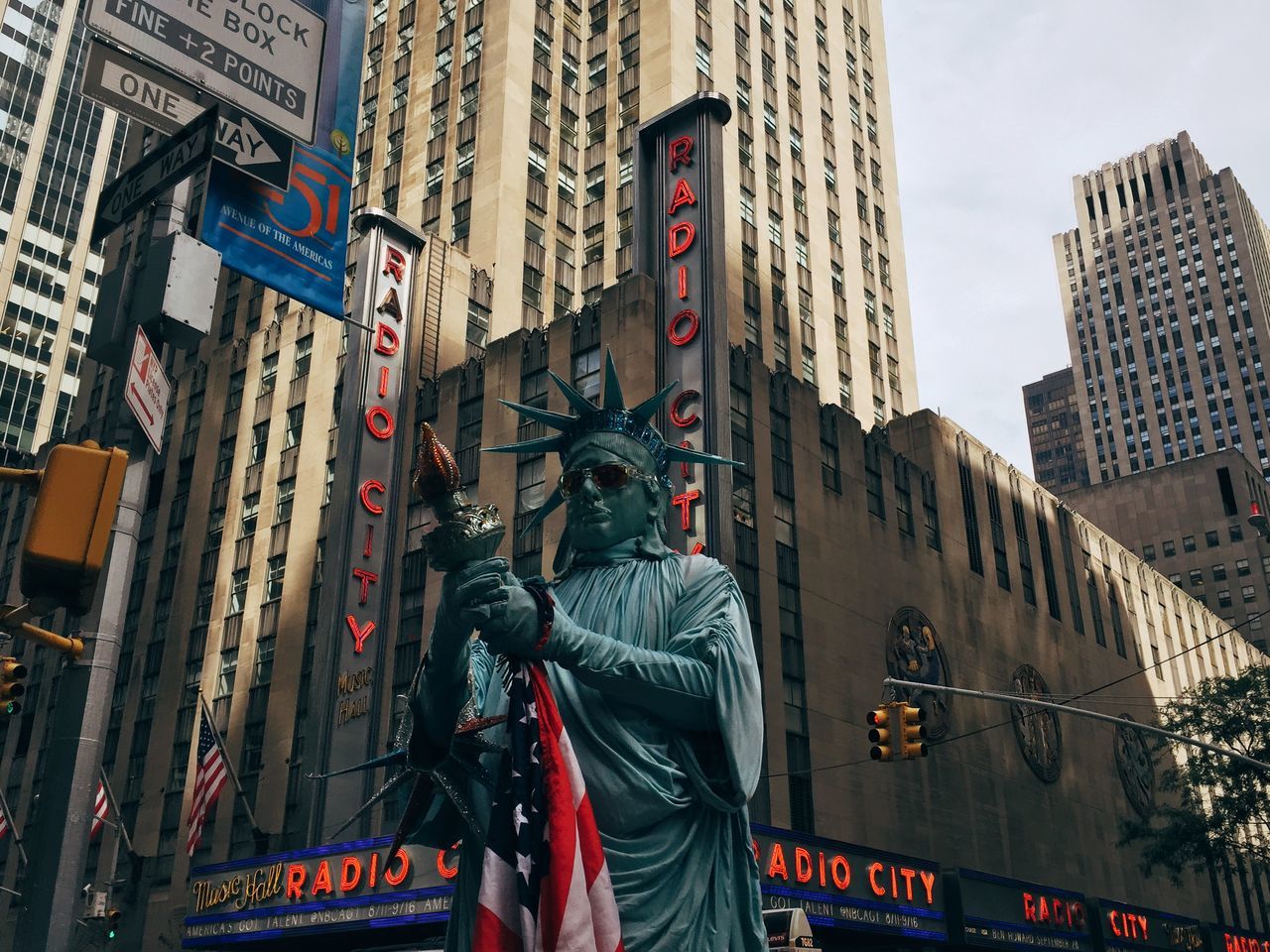 building exterior, architecture, built structure, text, city, western script, communication, low angle view, non-western script, building, flag, sign, information sign, road sign, skyscraper, day, city life, transportation, outdoors, american flag