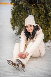 Portrait of young woman sitting on snow covered field