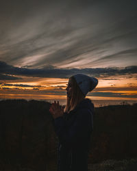 Woman standing by sky during sunset