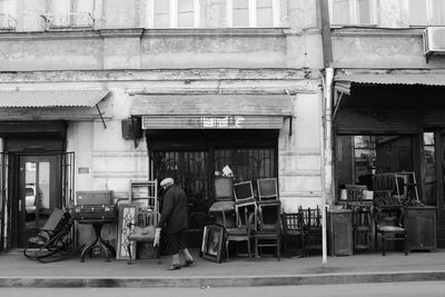 Man walking on sidewalk with old furniture at antique shop