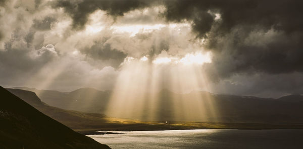 Sunlight streaming through clouds over mountain