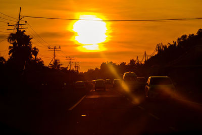 Cars on road against sky during sunset