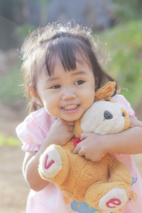 Cute girl embracing teddy bear while standing outdoors