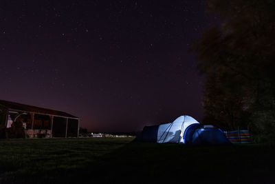 Illuminated tents on field against sky at night