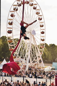 People in amusement park ride against sky