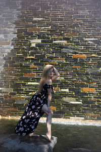 Side view of woman against brick wall