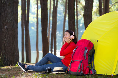 Girl sits next to a tent listening to music from pink headphones, pang oung, mae hong son, thailand.