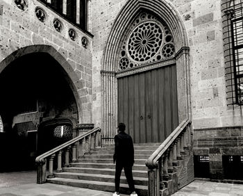 Full length rear view of man walking on staircase outside building