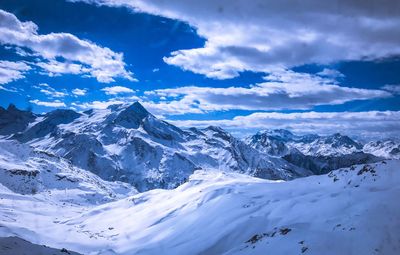 Scenic view of snow mountains against blue sky