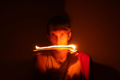 Close-up portrait of young man holding lit candle