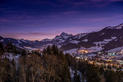 Scenic view of snowcapped mountains and town against sky at night