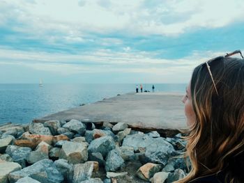 Woman on rocks at beach against sky