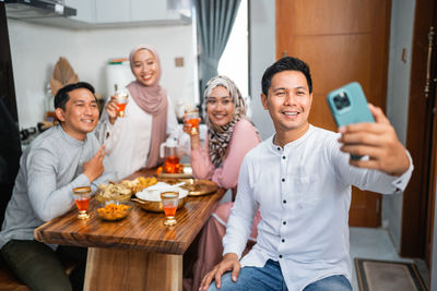 Female friends using mobile phone while sitting on table