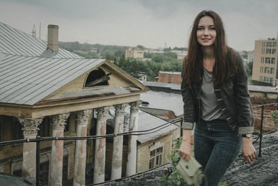 Portrait of smiling young woman standing against house