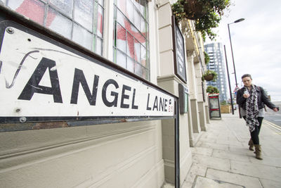 Man walking on footpath against building in city