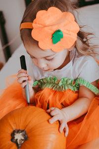 Little toddler girl drawing on a pumpkin making lantern jack on halloween holiday. 