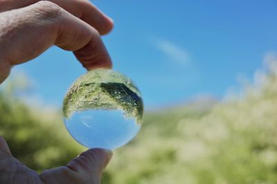 Close-up of human hand against blue sky