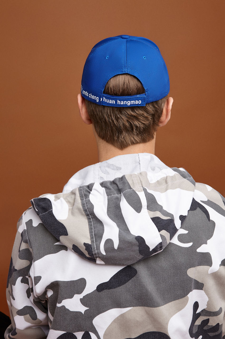 REAR VIEW OF BOY WITH HAT WEARING MASK