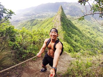 Full length of shirtless man descending steep ridge 