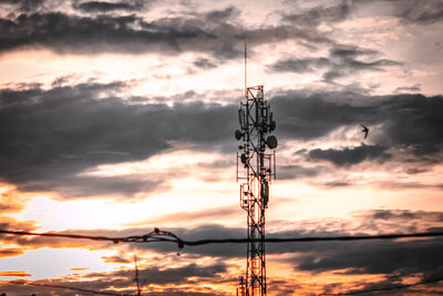 Low angle view of silhouette electricity pylon against sky during sunset