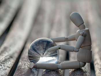 Close-up of human figurine with crystal ball on wooden chair