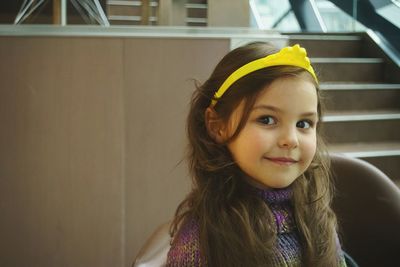 Close-up portrait of cute girl wearing yellow headband while sitting on chair