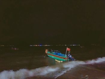 Boat sailing in sea against sky at night