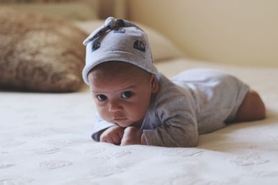 Portrait of cute baby boy lying on bed at home