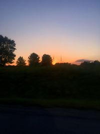 Silhouette of trees on landscape at sunset