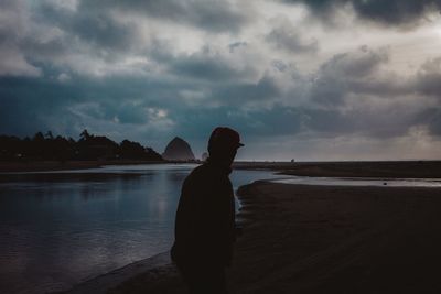 Silhouette man standing on beach against sky