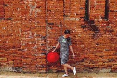 Young woman walking by brick wall
