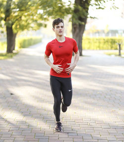 Portrait of young man running on footpath