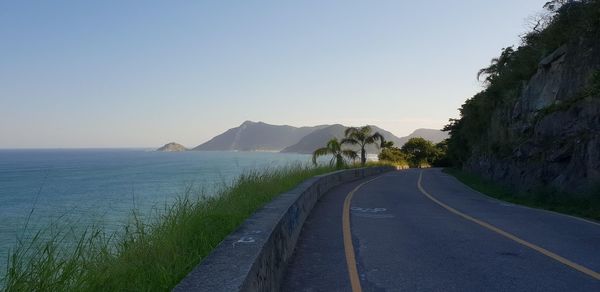 Road by sea against clear sky